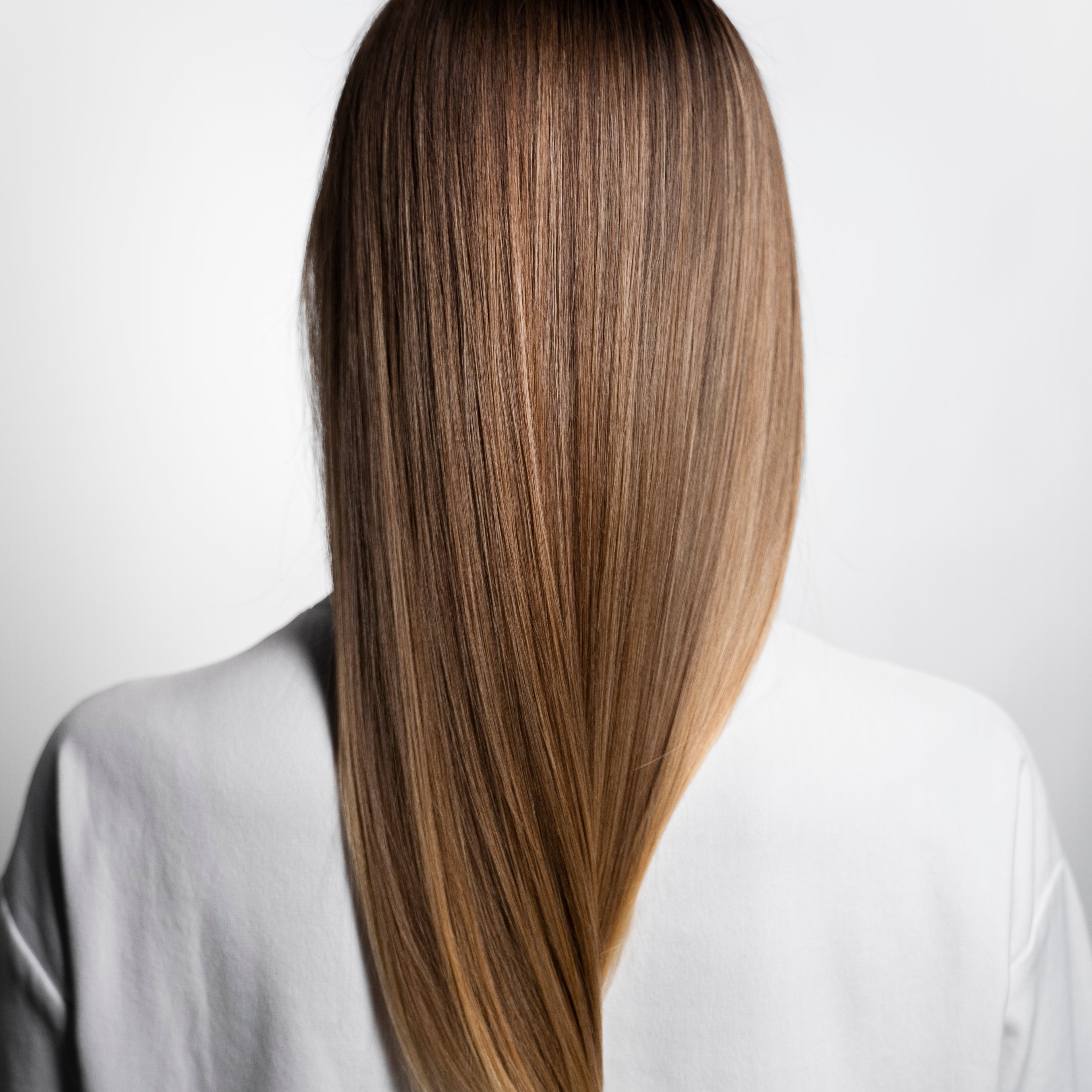 Detailaufnahme von perfektem, glattem und glänzendem braunem Haar von hinten – Zeigt das natürliche Ergebnis und die sichtbare Qualität von handverlesenem Remy-Echthaar bei Rovia Hair in Basel.