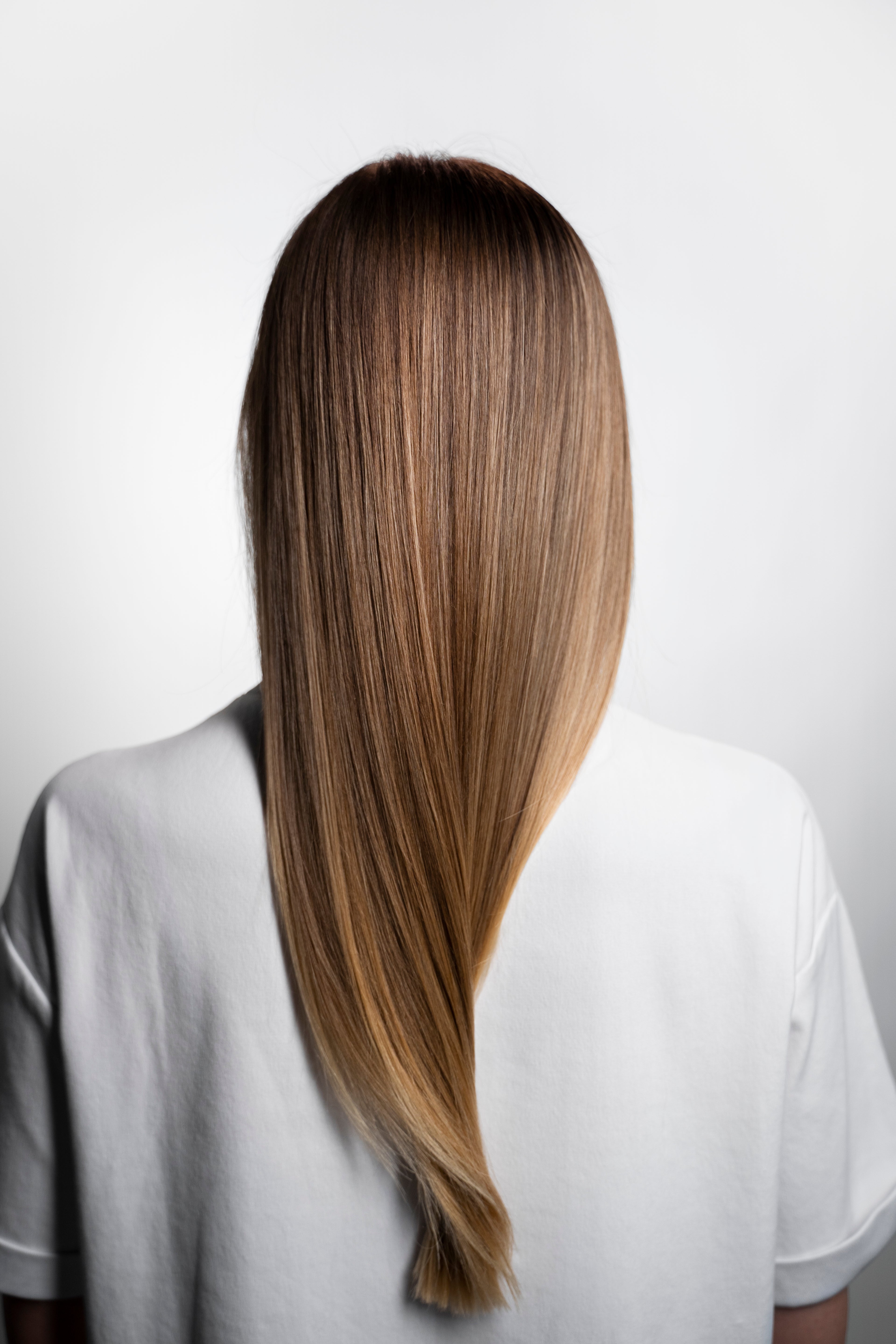Detailaufnahme von perfektem, glattem und glänzendem braunem Haar von hinten – Zeigt das natürliche Ergebnis und die sichtbare Qualität von handverlesenem Remy-Echthaar bei Rovia Hair in Basel.